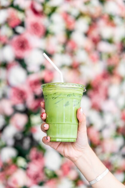 mano che tiene la tazza di tè verde del latte matcha ghiacciata