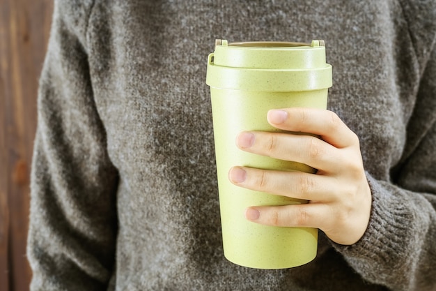 Mano che tiene le mani riutilizzabili eco tazza di caffè