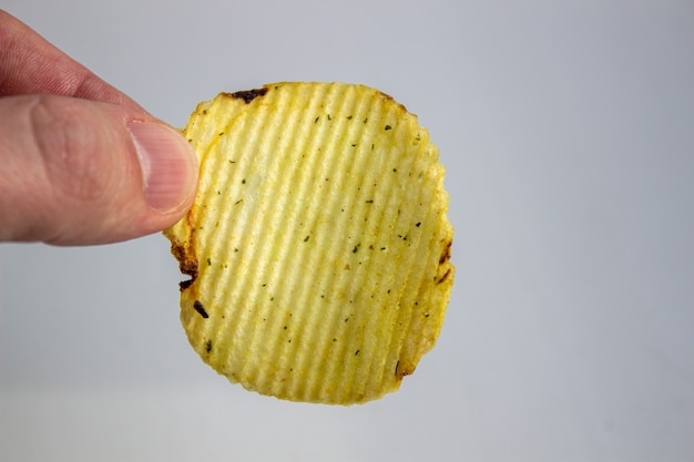 Mano che tiene le patatine fritte isolate su bianco.