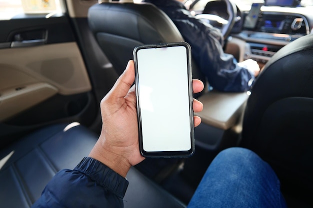 mano che tiene lo smartphone con lo schermo vuoto in un'auto