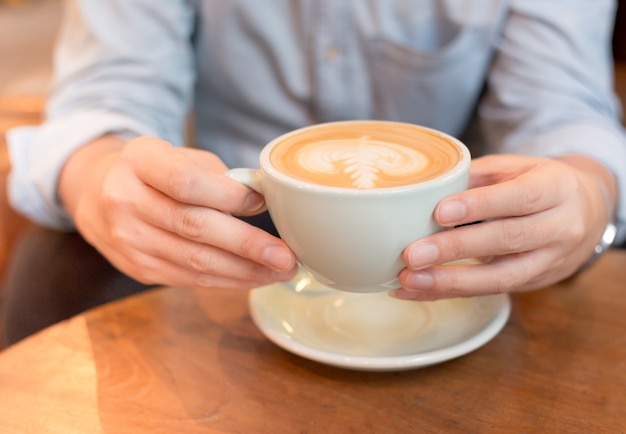 mano che tiene tazza di caffè caldo