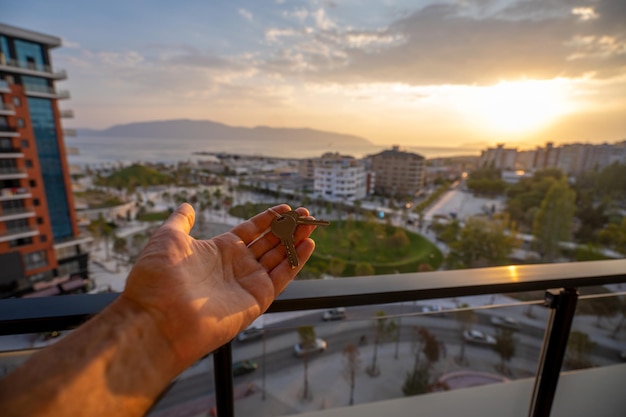 Mano che tiene tre chiavi sopra la mano su sfondo tramonto Concetto di edificio