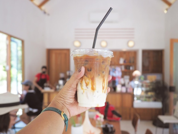 Mano che tiene un bicchiere di caffè ghiacciato nella caffetteria