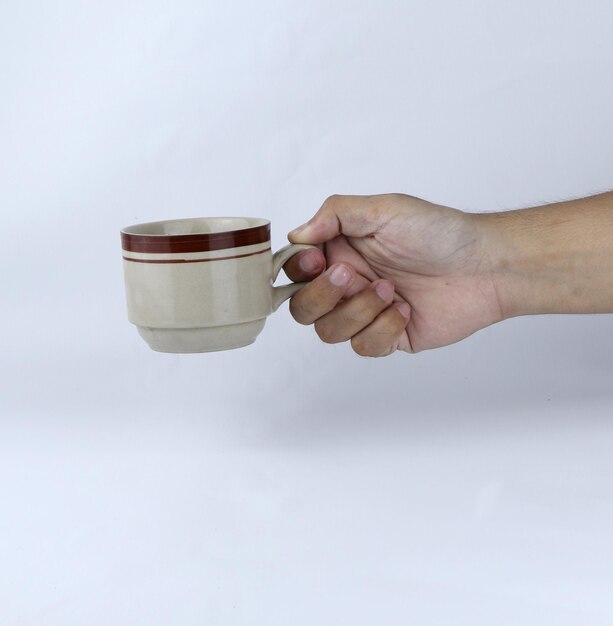 mano che tiene un bicchiere di tazza su uno sfondo bianco