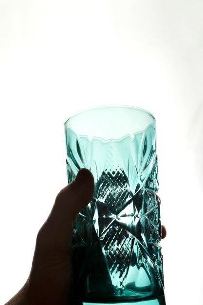 Mano che tiene un vaso di vetro con ornamenti con luce dietro