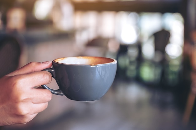 mano che tiene una tazza blu di caffè caldo