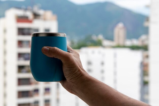 Mano che tiene una tazza d'acqua con vista sullo sfondo della città