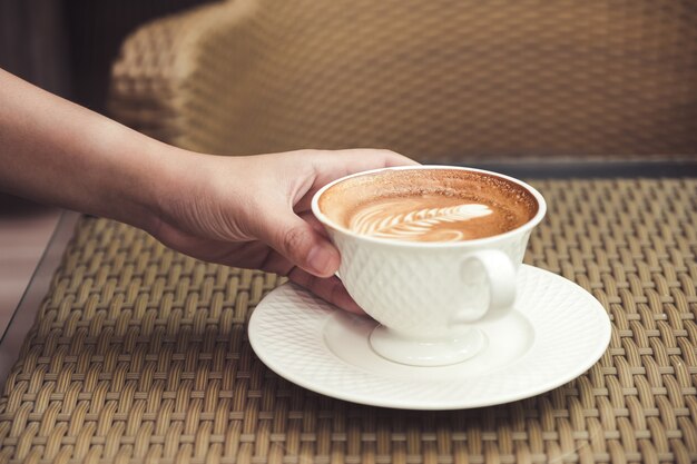 Mano che tiene una tazza di caffè caldo