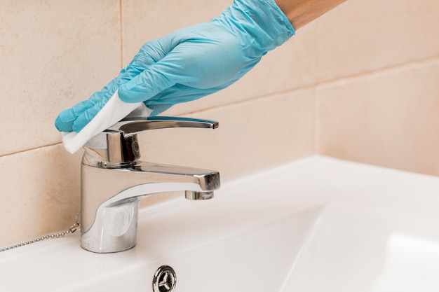 Mano con guanto chirurgico disinfettante per lavandino del bagno