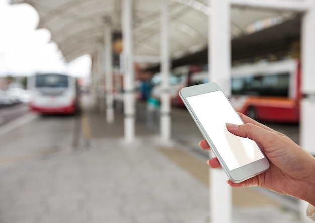 Mano con il cellulare nella stazione degli autobus