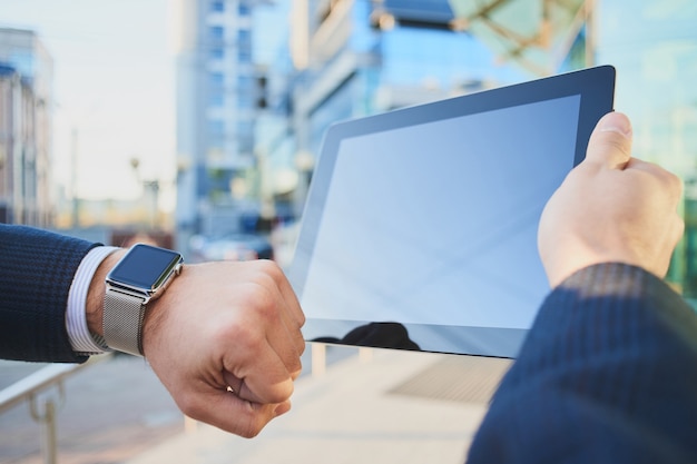 Mano con orologio intelligente e una mano che tiene il tablet