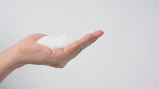 Mano con sapone per le mani schiumogeno e bolla per lavare e risciacquare su sfondo bianco.