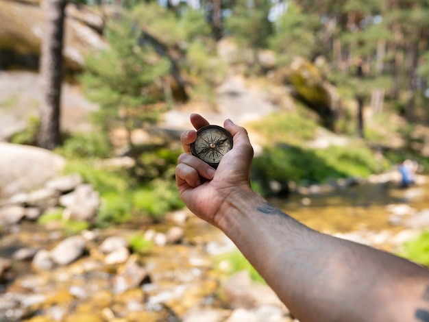 Mano con una bussola vicino al fiume