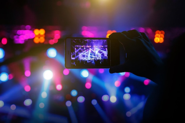 Mano con uno smartphone registra il festival di musica dal vivo e scatta foto del palco del concerto