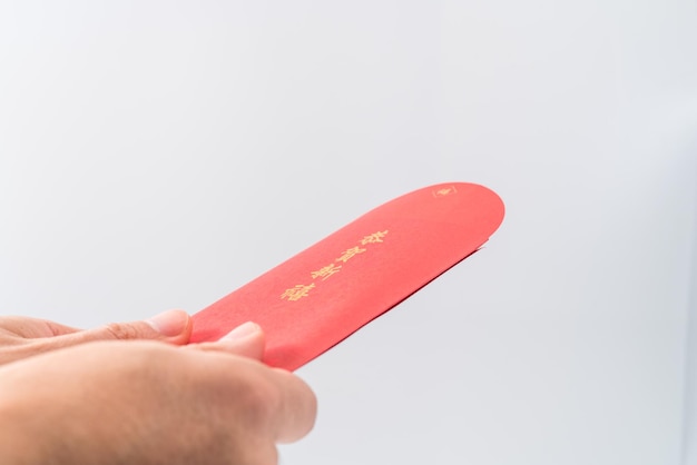 Mano d'uomo che tiene con la busta rossa cinese (pacchetto rosso). Concetto cinese del nuovo anno. (Cinese "GÅ nghÃ¨ xÄ«nxÇ" su di esso significa "Ti auguro prosperità")