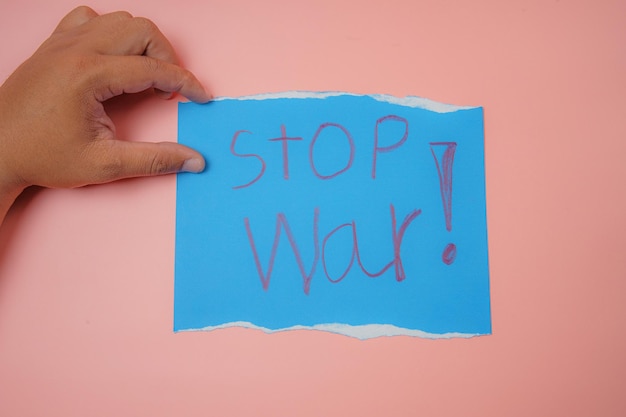 Mano d'uomo che tiene una carta blu con il testo stop war su uno sfondo rosa