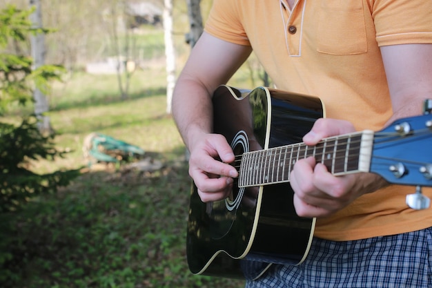 Mano d'uomo con corde di chitarra all'aperto