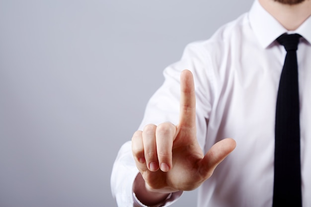 Mano d'uomo indossa una camicia bianca e cravatta che mostra un segno in studio