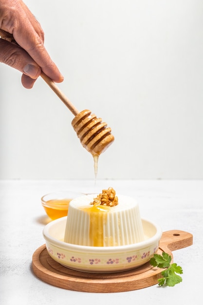 Mano d'uomo versando il miele in un formaggio fresco