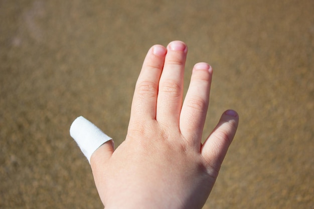 Mano dei bambini con un cerotto sul dito Cerotto medico sulla mano di un bambino Lesioni al dito del bambino