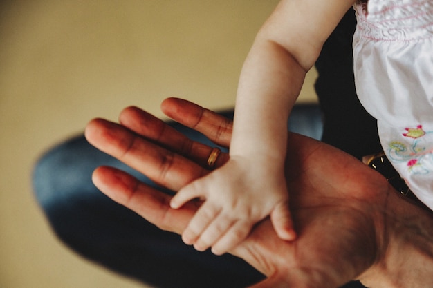 Mano del bambino piccolo sul palmo di papà in primo piano. Il padre tiene la mano del neonato in mano. Famiglia: mani del genitore e del bambino. Concetto di genitorialità, cure parentali e festa del papà. Copia spazio per il sito di immagini