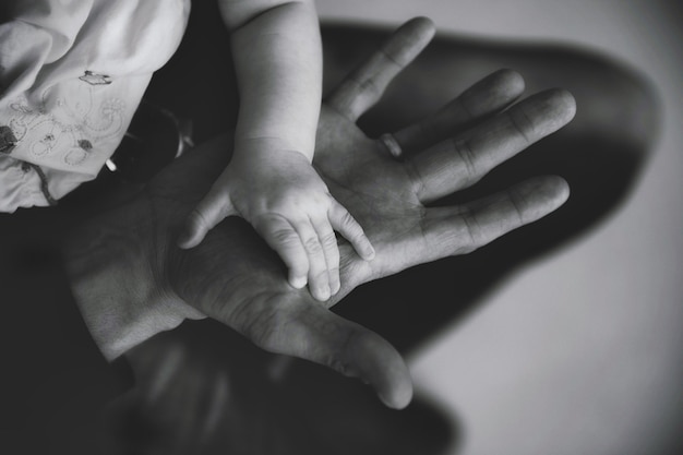 Mano del bambino piccolo sul palmo di papà in primo piano. Il padre tiene la mano del neonato in mano. Famiglia: mani del genitore e del bambino. Concetto di genitorialità, cure parentali e festa del papà. Copia spazio per il sito di immagini