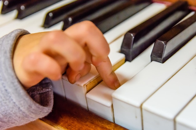 Mano del bambino sui tasti lucidi del pianoforte