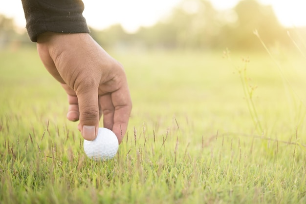 Mano del giocatore di golf asiatico che tiene golf su prato La gente gioca a golf sul tramonto