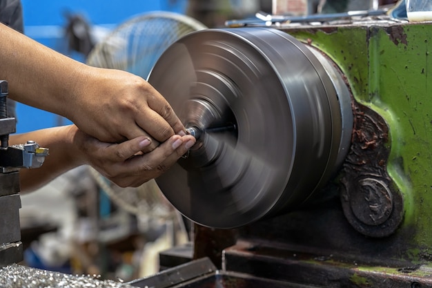 Mano del macchinista del primo piano che funziona con la macchina dei torni nella fabbrica di lavorazione dei metalli