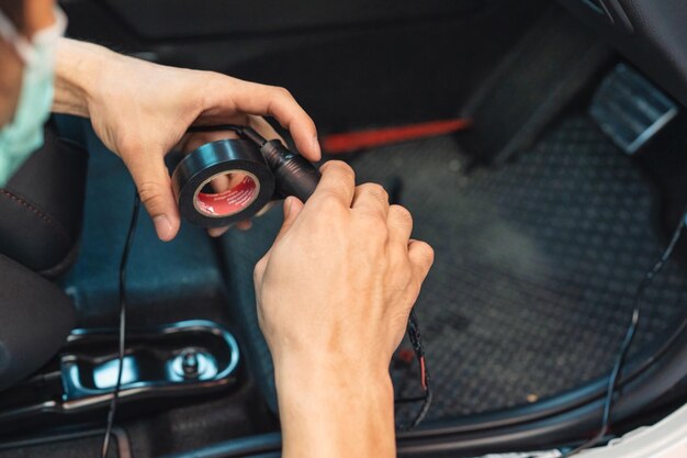 Mano del meccanico che utilizza il filo di avvolgimento del nastro adesivo dell'auto per installare il dispositivo