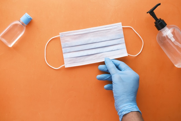 Mano del medico nel guanto medico che tiene la maschera chirurgica protettiva da vicino