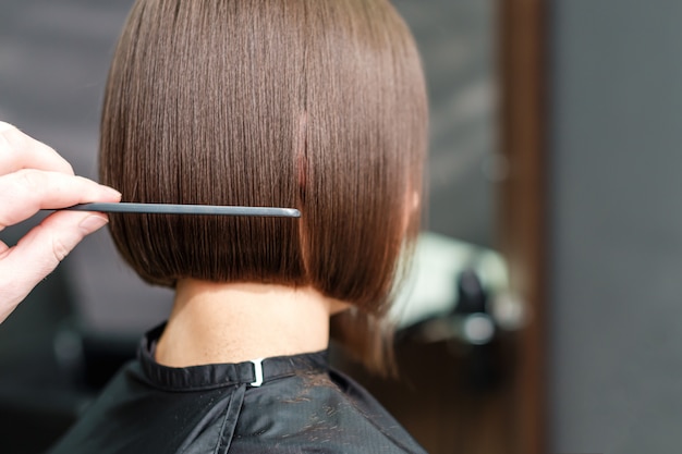 Mano del parrucchiere che pettina i capelli della donna