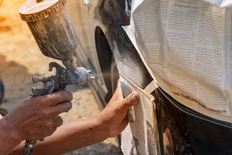 Mano del pittore riparatore di automobili con polverizzatore aerografo