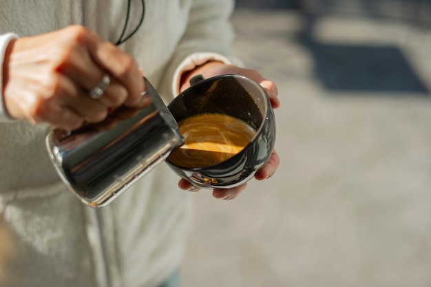 Mano del primo piano che fa caffè caldo di arte del latte