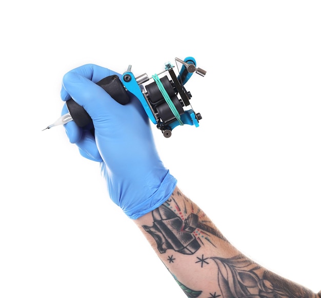 Mano del tatuatore nel guanto blu con la macchina del tatuaggio isolata su fondo bianco si chiuda