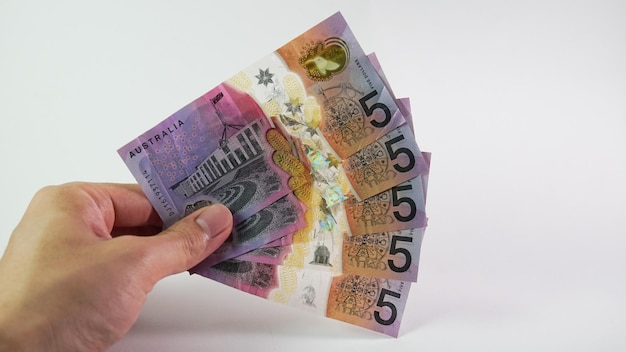 Mano dell'uomo asiatico che tiene un dollaro australiano isolato su priorità bassa bianca