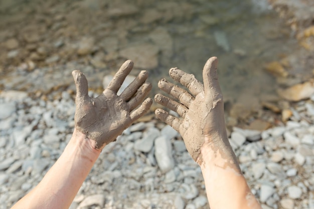 Mano dell'uomo che imbratta il fango curativo nero sul braccio Primo piano