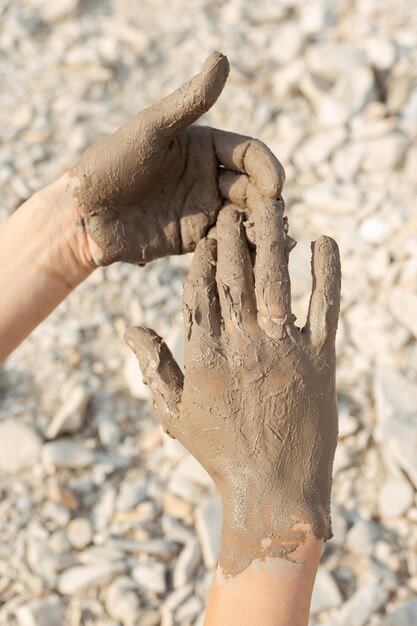 Mano dell'uomo che imbratta il fango curativo nero sul braccio Primo piano