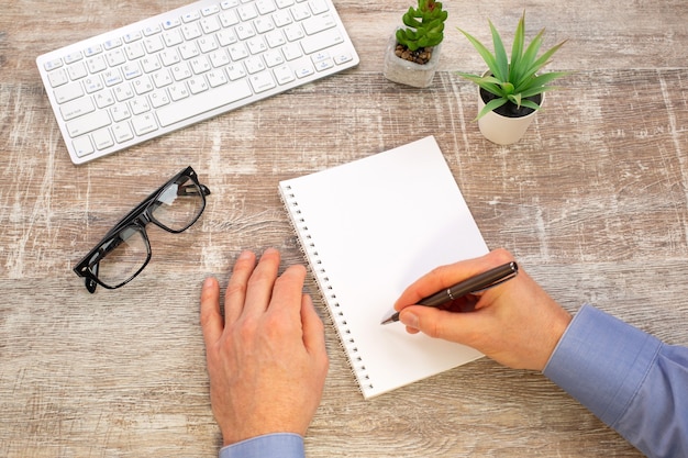 Mano dell'uomo che scrive nel blocco note a spirale bianco