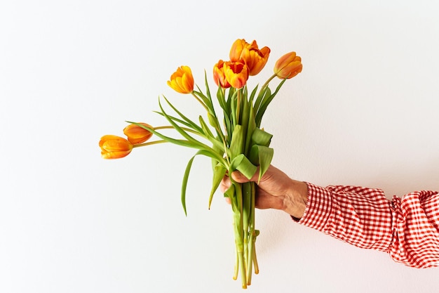 Mano dell'uomo che tiene bouquet di tulipani primaverili arancioni