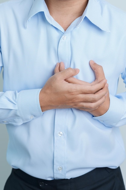 Mano dell'uomo che tiene il dolore al petto Malattia cardiaca Malattia angina e sintomo Malattia da attacco cardiaco Aterosclerosi cardiovascolare Ipertensiva Giornata mondiale del cuore e concetto di salute