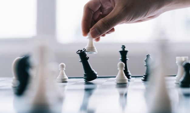 Mano dell'uomo d'affari asiatico muovendo la figura di scacchi nel gioco di successo della concorrenza