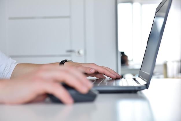 Mano dell'uomo d'affari facendo uso del mouse e digitando una tastiera del computer portatile