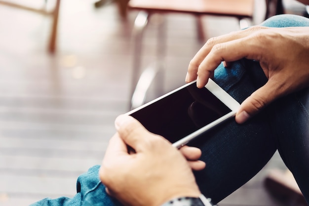 Mano dell&#39;uomo d&#39;affari facendo uso del telefono cellulare alla caffetteria nella luce di mattina