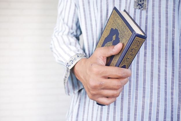 Mano dell'uomo musulmano con il libro sacro Corano con copia spazio