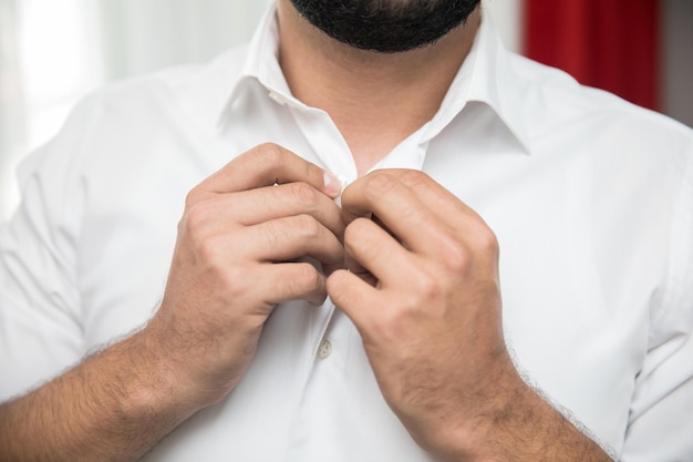 Mano dell'uomo nel bottone della camicia nel roomxA