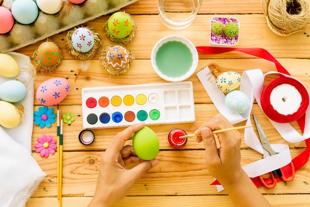 Mano della donna che dipinge le uova di Pasqua. Famiglia felice che prepara per Pasqua.