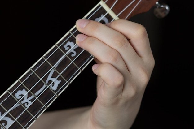 Mano della donna che gioca ukulele sullo sfondo nero