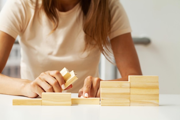 Mano della donna che organizza l'impilamento del blocco di legno come scala a gradini