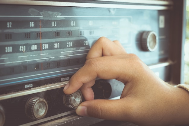 Mano della donna che regola la ricevente radiofonica d&#39;annata del bottone